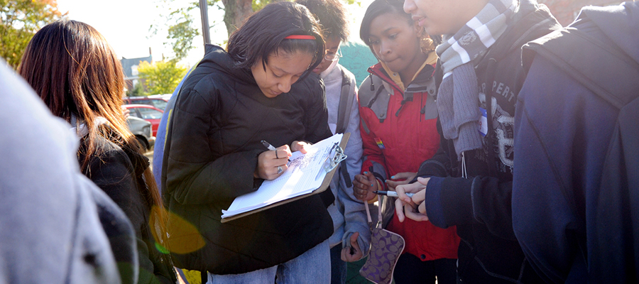 Young people filling out something on a clipboard