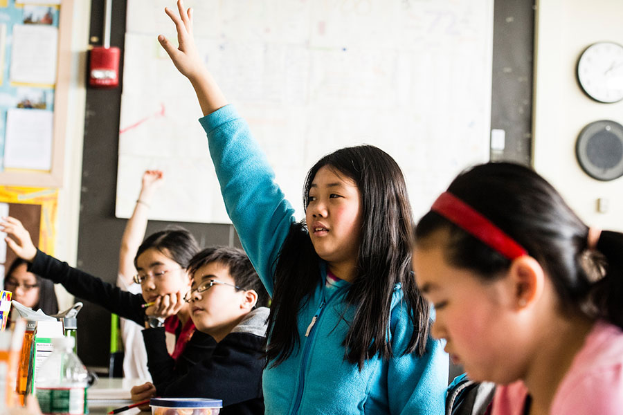 child raising her hand in classroom