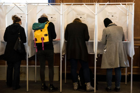 Four college students voting at voting booths